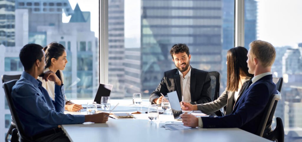 A diverse team of professional project managers and contractors in a high-rise office discussing a construction project.