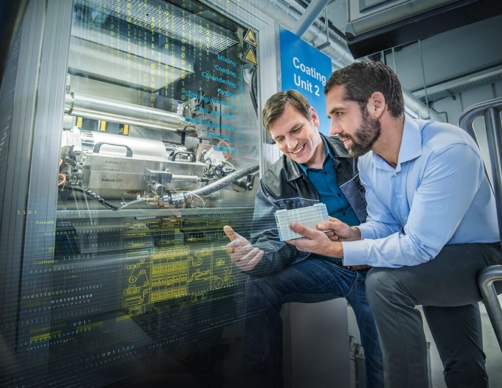 Two industrial engineers inspecting a digital interface and high-tech coating machinery inside a modern manufacturing facility.